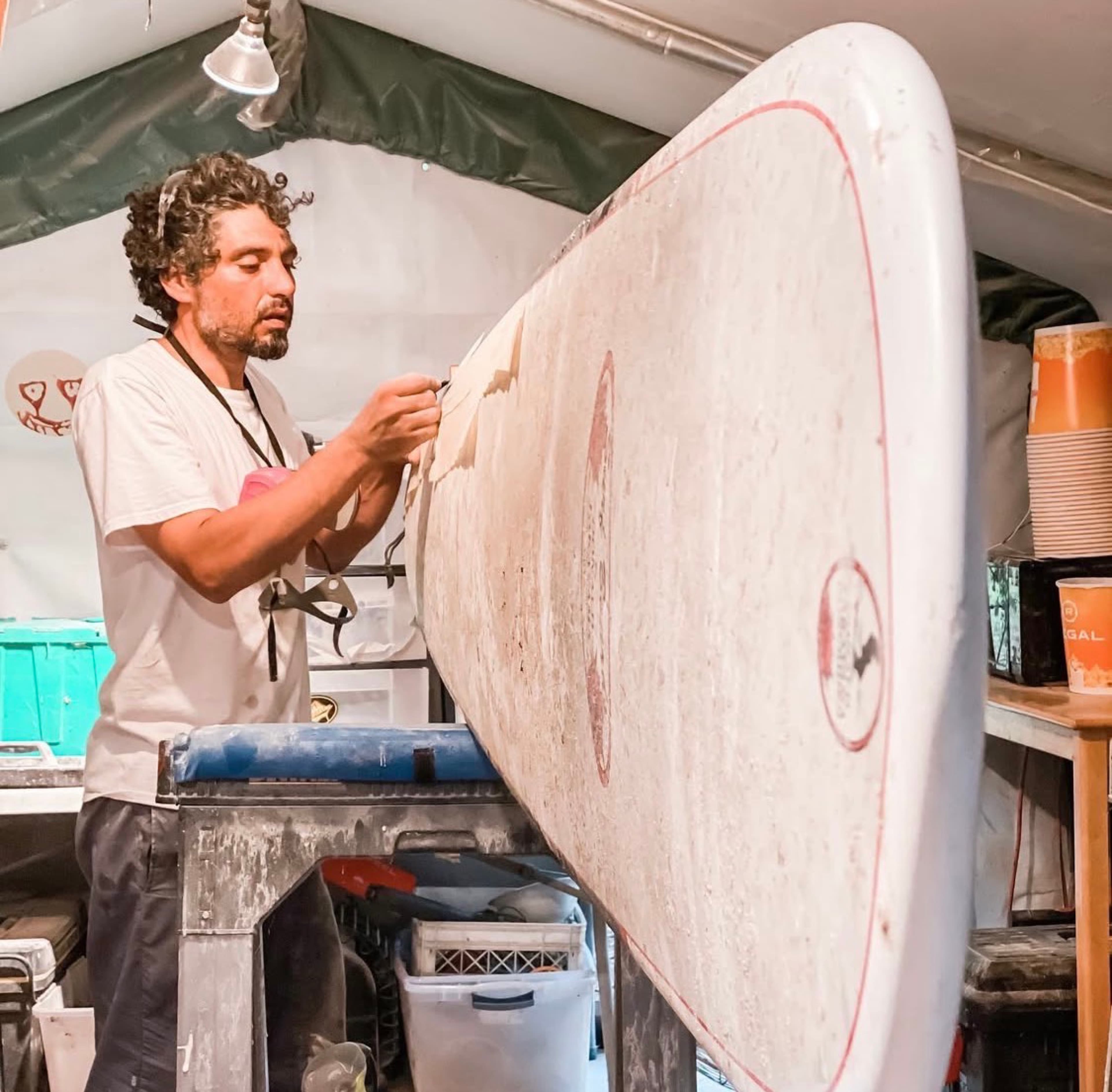 Strictly Surf repair technician taping a longboard during restoration in the Amagansett workshop