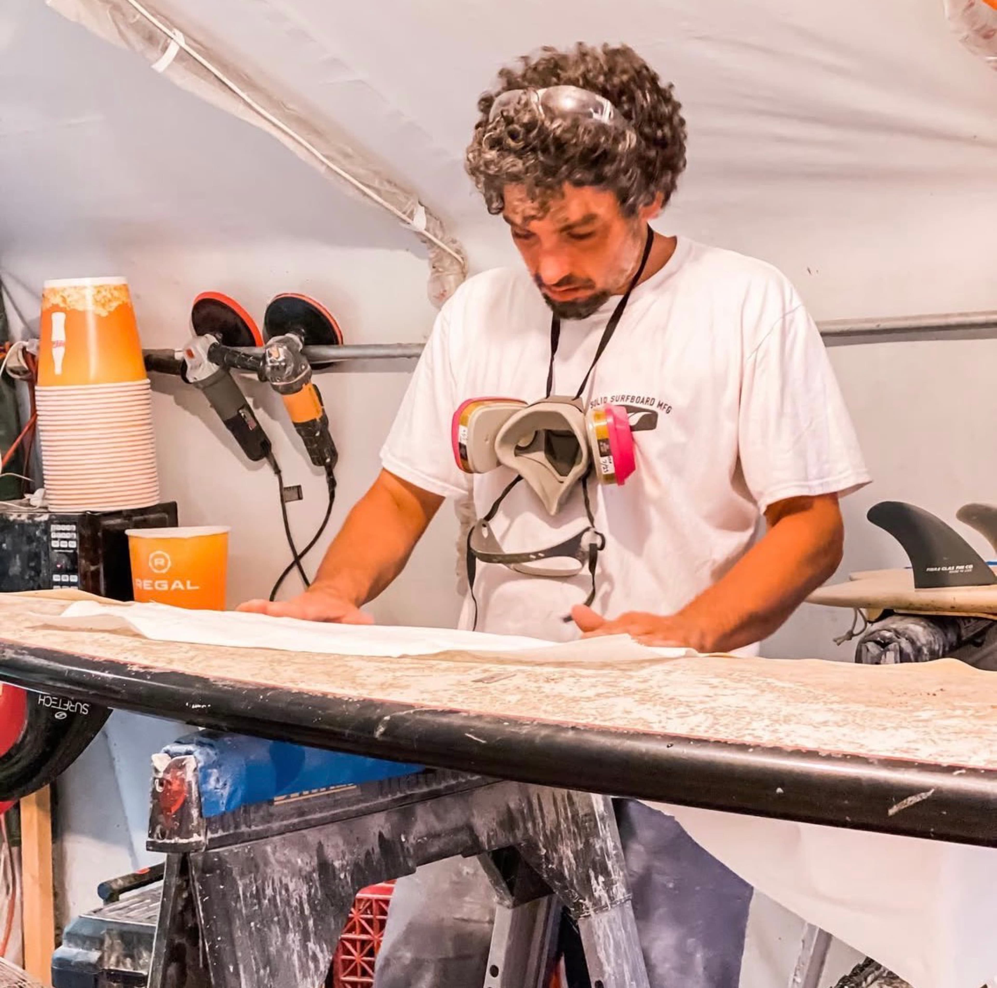 Strictly Surf technician laminating fiberglass on a surfboard at the Amagansett workshop