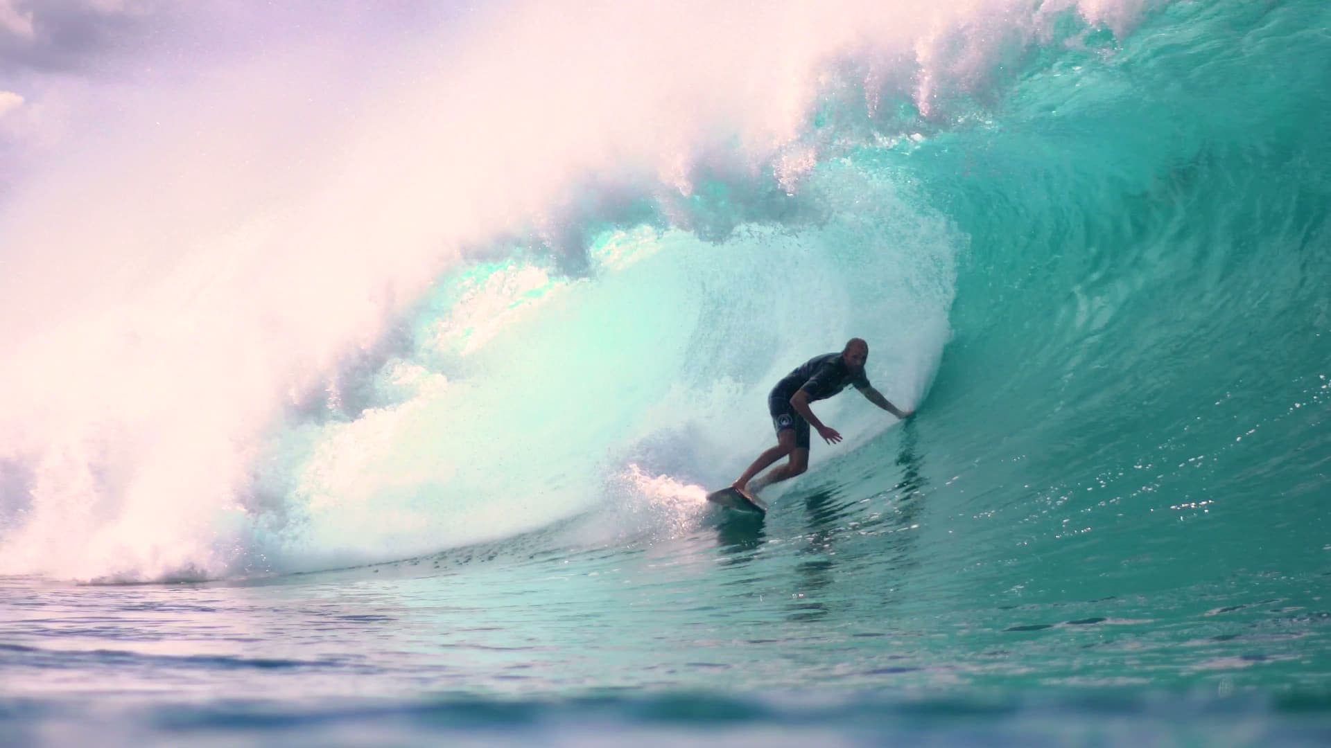 Surfer riding a clean wave at sunrise