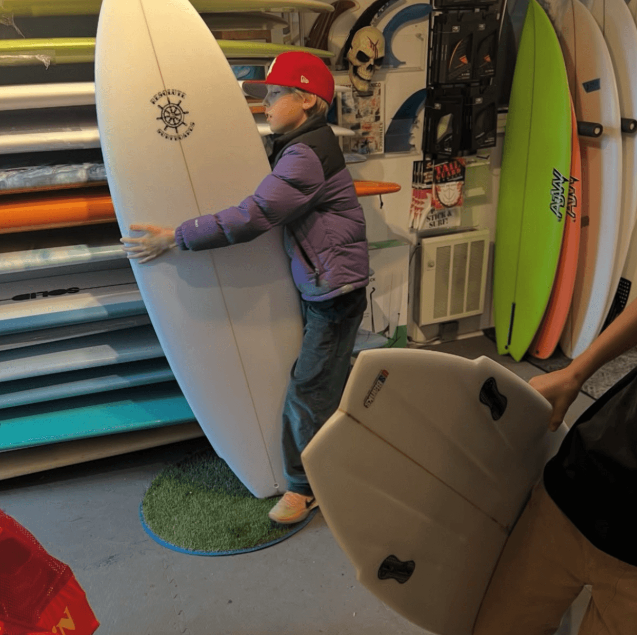 Young rider hugging a surfboard inside the Strictly Surf shop