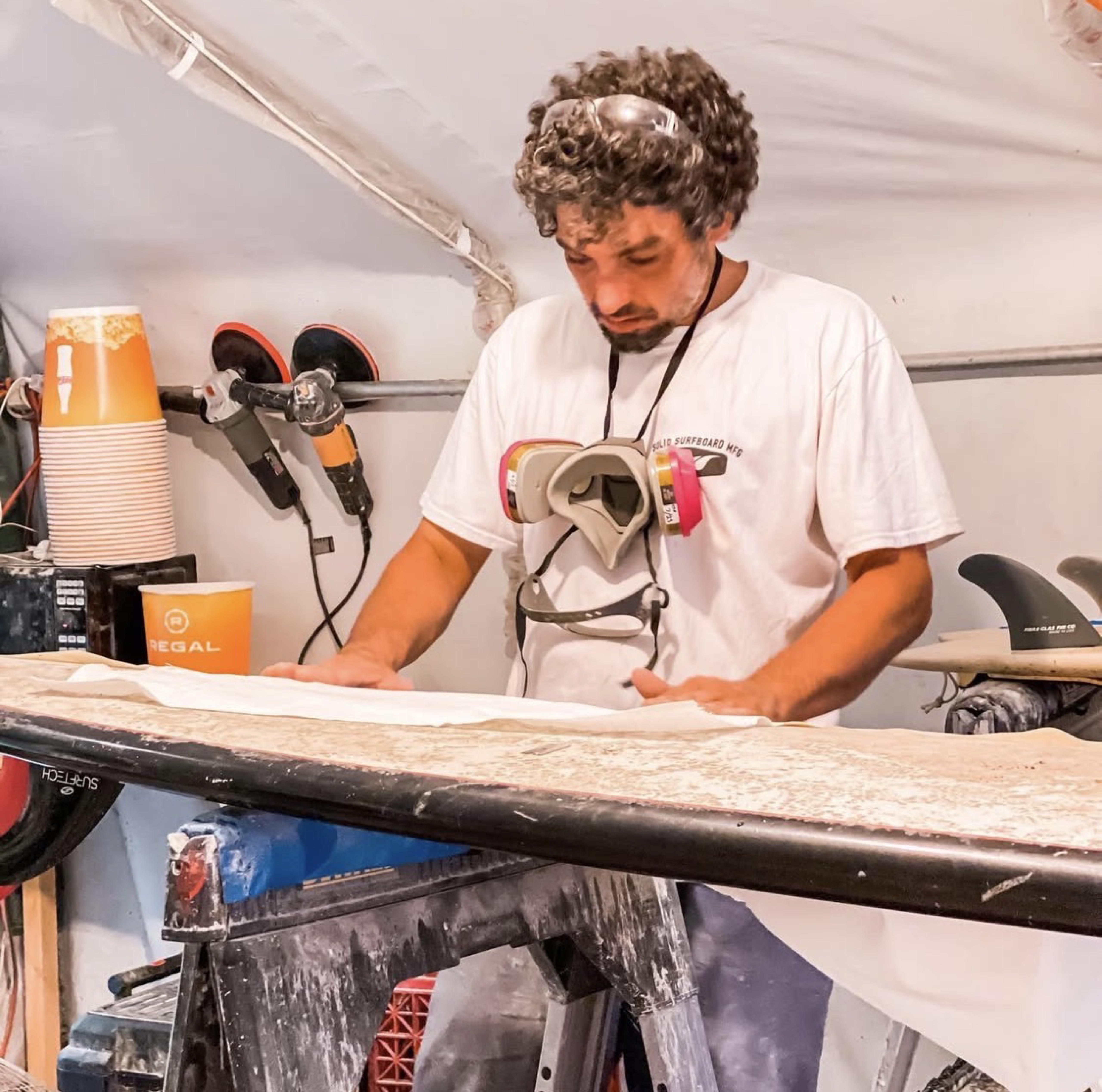 Strictly Surf technician laminating fiberglass on a surfboard at the Amagansett workshop